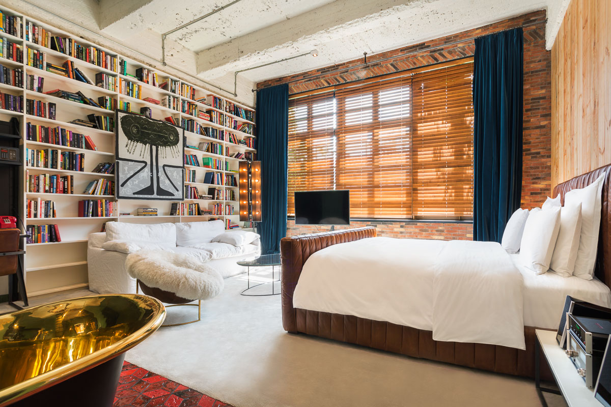 stamba hotel aviator signature room with bed bookshelves and wide window